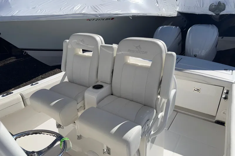 Slide: The Image of 2023 Regulator 28 boat interior with dual white captain's chairs and twin engines. - 14