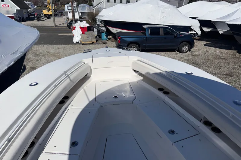 Slide: The Image of 2023 Regulator 28 boat deck with seating, parked near covered boats and a truck. - 15