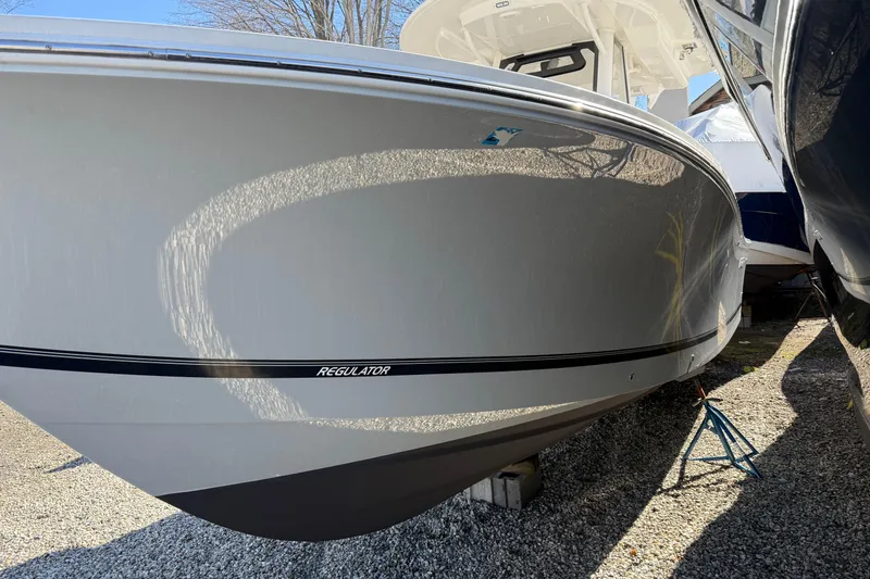 Slide: The Image of 2023 Regulator 28 boat on gravel, side view, showcasing sleek design. - 2