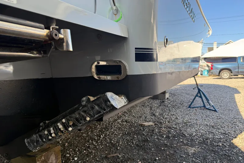 Slide: The Image of 2023 Regulator 28 boat hull detail with trim tabs, parked on gravel. - 22