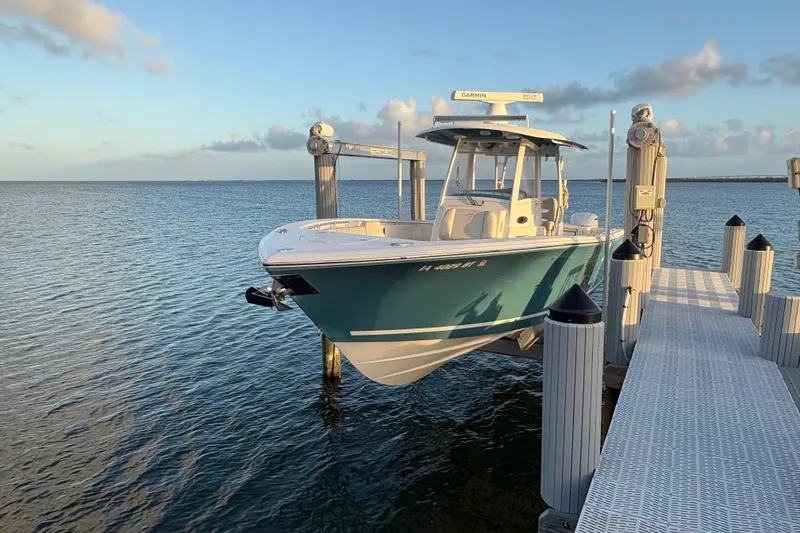 The Image of 2019 Cobia 320 Center Console boat docked on calm water at sunset. - 1
