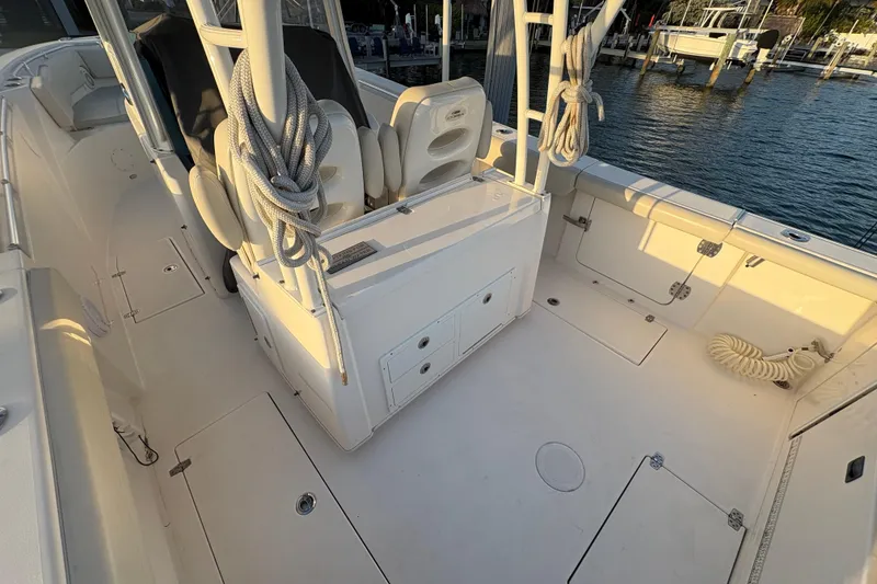 Slide: The Image of 2019 Cobia 320 Center Console boat interior with seating and storage, docked by the water. - 10