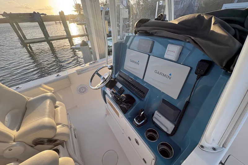 Slide: The Image of 2019 Cobia 320 Center Console helm with Garmin displays, overlooking serene waterfront at sunset. - 13