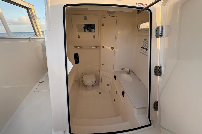 Slide: The Image of 2019 Cobia 320 Center Console boat interior with compact bathroom and sink. - 18