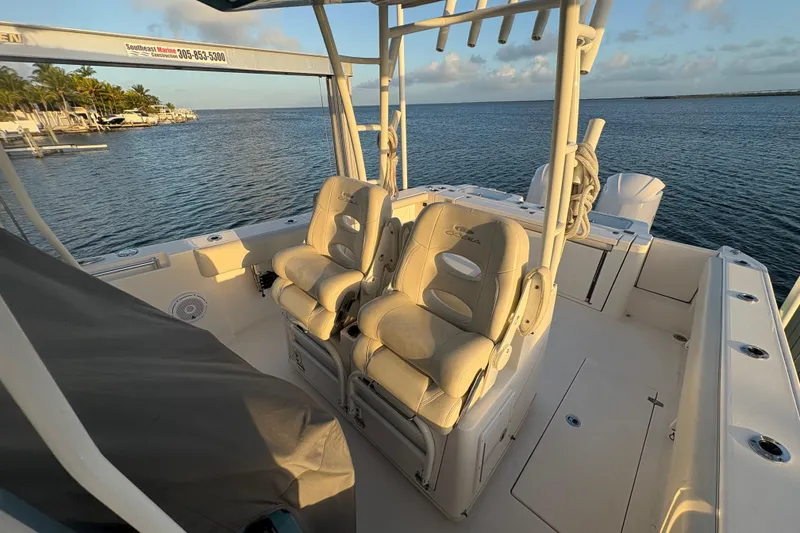 Slide: The Image of 2019 Cobia 320 Center Console boat interior with dual seats, docked by the ocean. - 19