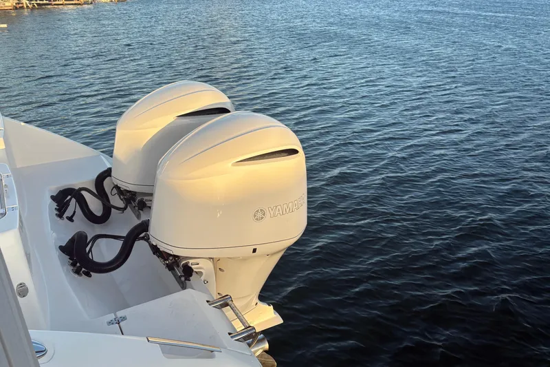 Slide: The Image of Twin Yamaha outboard engines on a 2019 Cobia 320 Center Console boat, docked on calm water. - 5