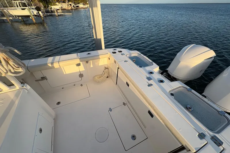 Slide: The Image of 2019 Cobia 320 Center Console boat deck with twin engines, docked by the water. - 8