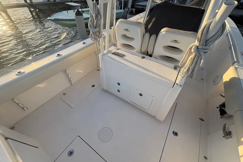 Slide: The Image of 2019 Cobia 320 Center Console boat interior with seating and storage, docked at sunset. - 9