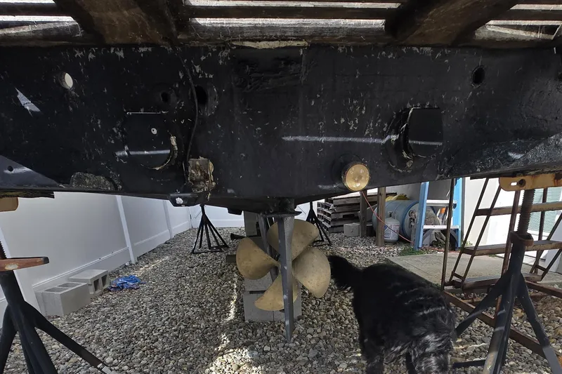 Slide: The Image of Underneath view of a 1992 Shamrock 260 Express boat on stands, with a dog nearby. - 13