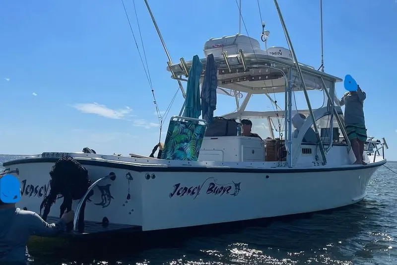 Slide: The Image of 1992 Shamrock 260 Express boat on water with people, fishing gear, and clear sky. - 2