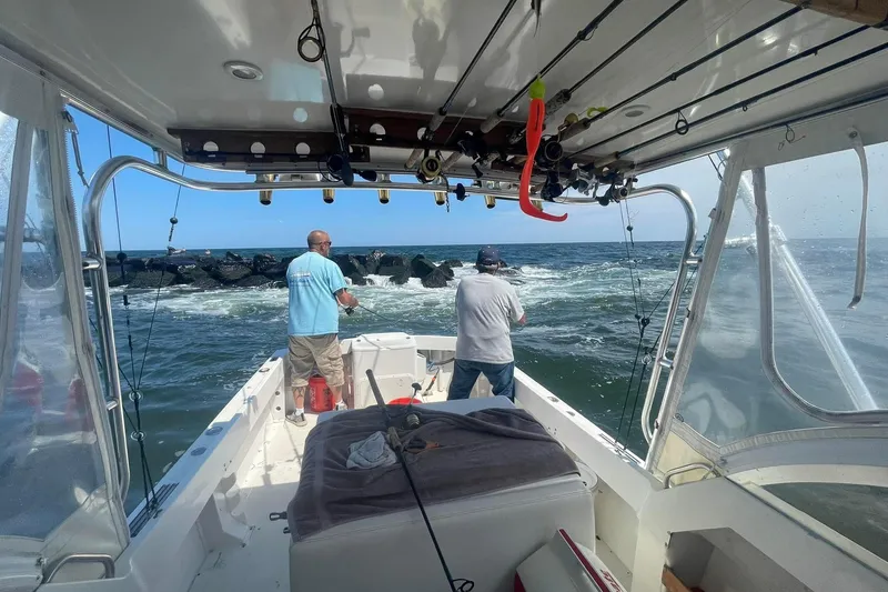 Slide: The Image of Two people fishing on a 1992 Shamrock 260 Express boat near rocky waters. - 5