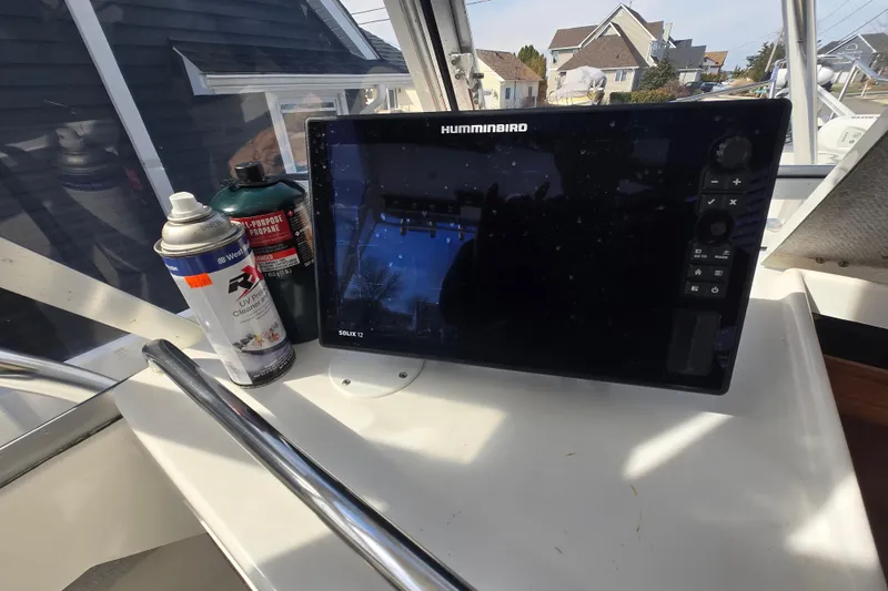 Slide: The Image of 1992 Shamrock 260 Express boat dashboard with Humminbird Solix 12 display and cleaning supplies. - 6