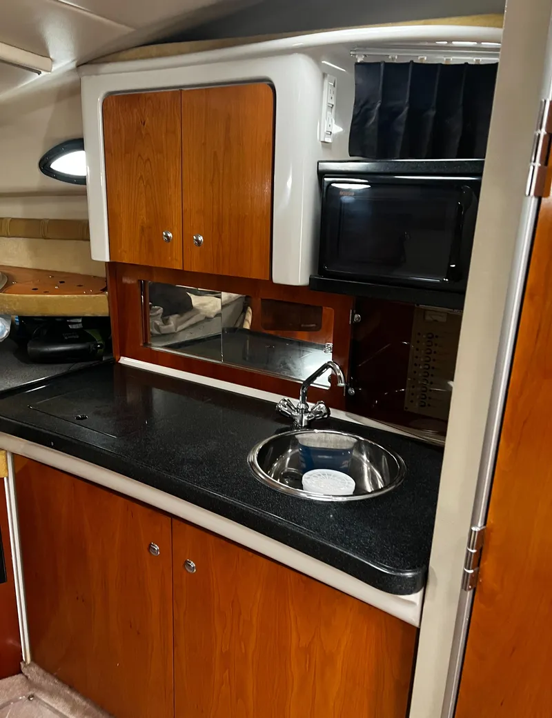 Slide: The Image of 2003 Regal Commodore 2860 boat kitchen with sink, microwave, and wooden cabinets. - 27