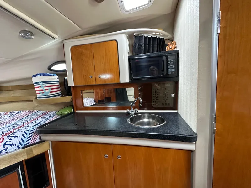 Slide: The Image of 2003 Regal Commodore 2860 boat interior kitchen with sink, microwave, and storage cabinets. - 28