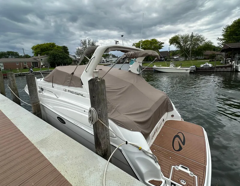 Slide: The Image of 2003 Regal Commodore 2860 boat docked at a marina under cloudy skies. - 8