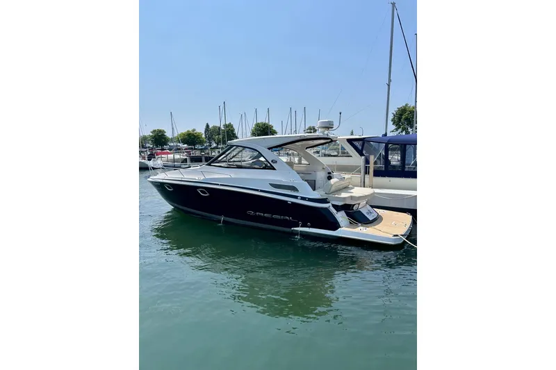 The Image of 2018 Regal 35 Sport Coupe yacht docked at marina under clear blue sky. - 0