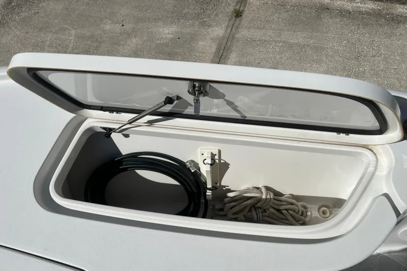 Slide: The Image of Open storage compartment on 2019 Sea Hunt BX 22 BR boat with rope and hose. - 30