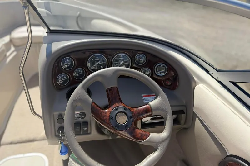 Slide: The Image of Dashboard of a 2004 Crownline 180 BR boat with wood-accented steering wheel. - 2