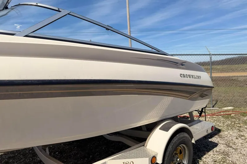 Slide: The Image of 2004 Crownline 180 BR boat on trailer, parked outdoors under clear sky. - 4
