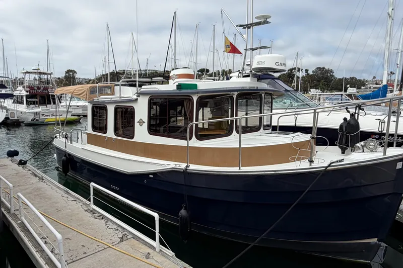 The Image of 2017 Ranger Tugs R-27 docked in a marina, surrounded by other boats. - 11