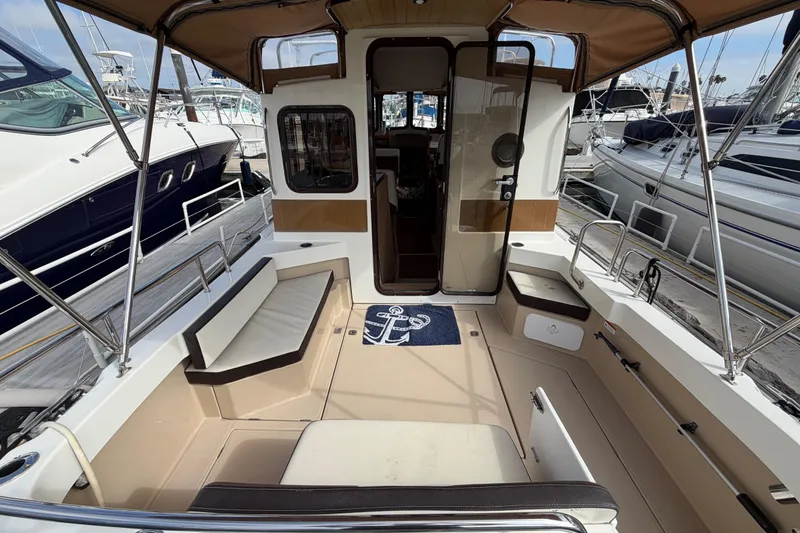 Slide: The Image of 2017 Ranger Tugs R-27 boat interior with seating and canopy at marina. - 13