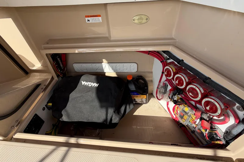 Slide: The Image of 2017 Ranger Tugs R-27 engine compartment with wiring, battery switches, and storage space. - 25