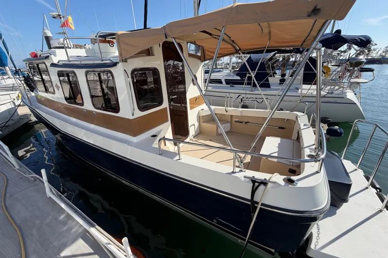 Slide: The Image of 2017 Ranger Tugs R-27 boat docked, featuring a spacious deck and canopy. - 27