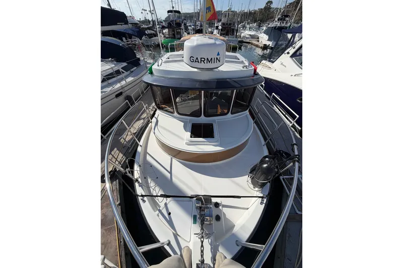 Slide: The Image of 2017 Ranger Tugs R-27 boat docked, featuring Garmin equipment, surrounded by other vessels. - 28