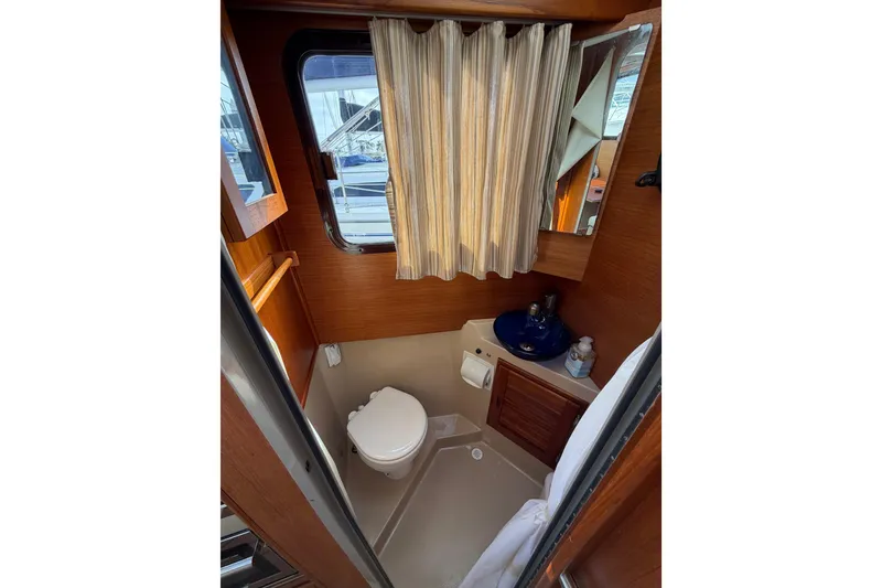 Slide: The Image of 2017 Ranger Tugs R-27 boat bathroom with toilet, sink, and window. - 29