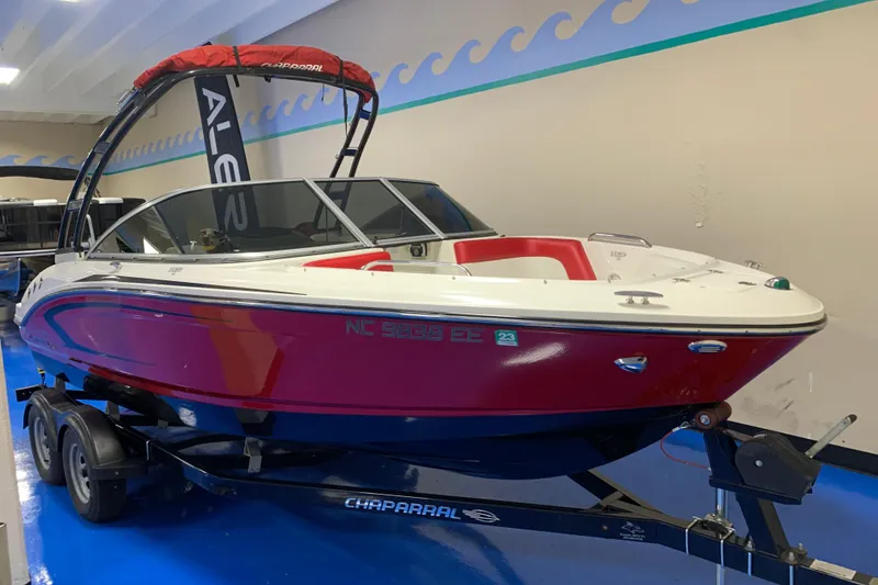 Slide: The Image of 2017 Chaparral 21 H2O Sport boat in showroom, red and white design on trailer. - 2