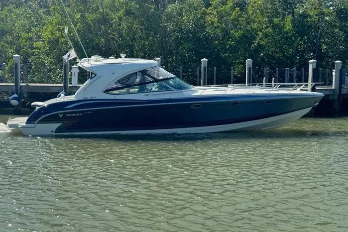Slide: The Image of 2017 Formula 400 Super Sport boat docked on calm water near a wooded shoreline. - 8