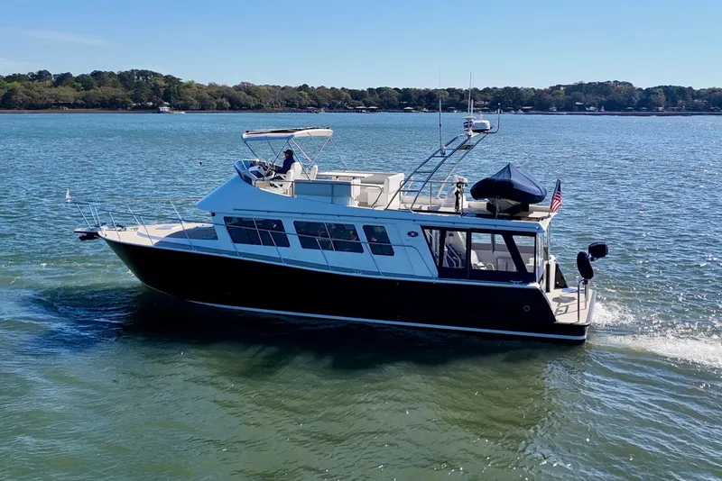 Slide: The Image of 2015 Coastal Craft 45 yacht cruising on a serene lake under clear blue skies. - 5