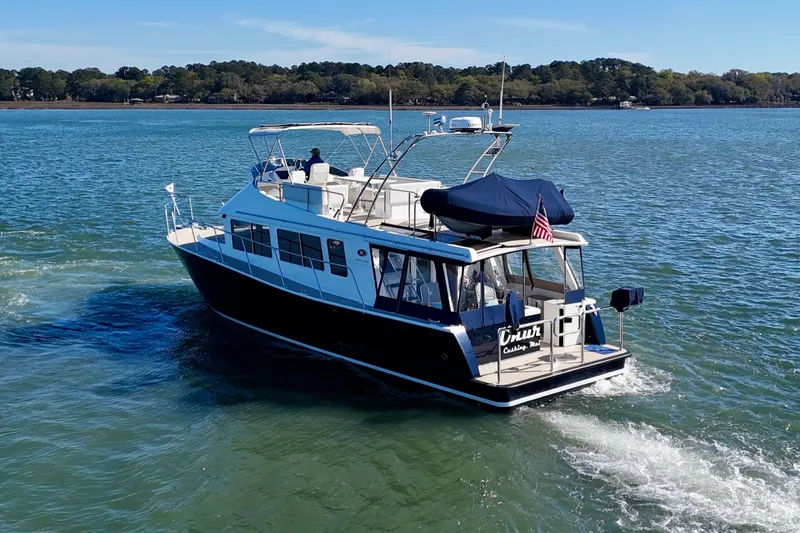 Slide: The Image of 2015 Coastal Craft 45 yacht cruising on a serene waterway with lush green shoreline. - 6