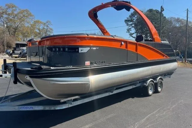 The Image of 2024 Bennington 23 RXFBA pontoon boat on trailer, featuring sleek orange and black design. - 1