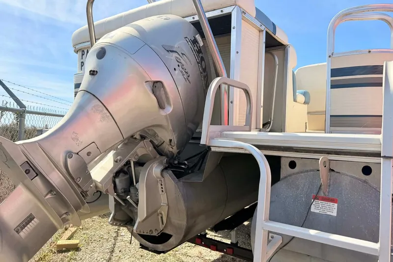Slide: The Image of Outboard motor on a 2004 Lowe Jamaica 250 boat, parked near a fence. - 5