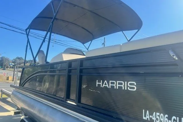 The Image of 2019 Harris Cruiser 250 pontoon boat on trailer, parked near a building. - 0