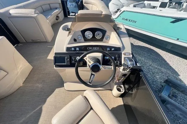 Slide: The Image of Open storage compartment on a 2019 Harris Cruiser 250 boat with beige seating. - 11