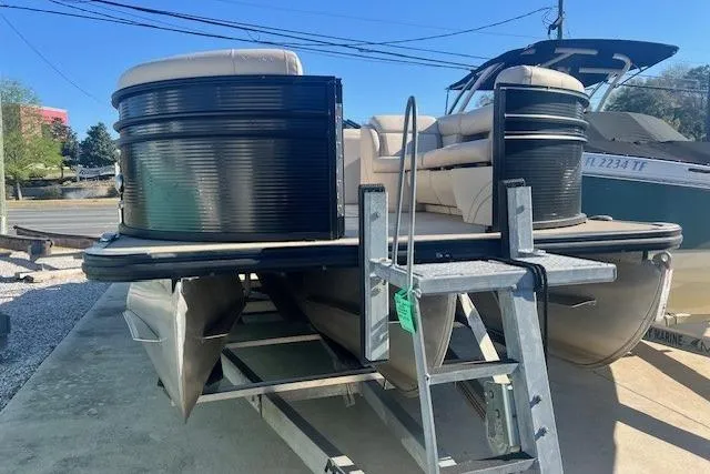 Slide: The Image of 2019 Harris Cruiser 250 pontoon boat on trailer, parked outdoors under clear blue sky. - 2