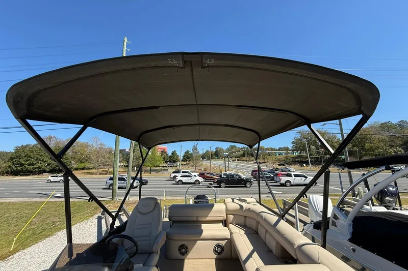 Slide: The Image of 2019 Harris Cruiser 250 pontoon boat with canopy, parked near a road. - 26