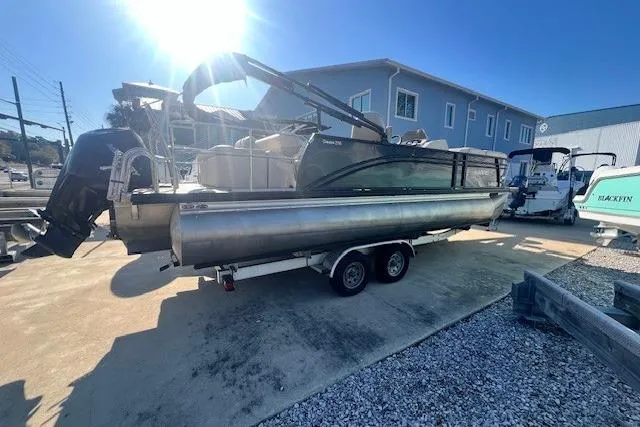 Slide: The Image of 2019 Harris Cruiser 250 pontoon boat with Mercury engine, parked on a trailer. - 3