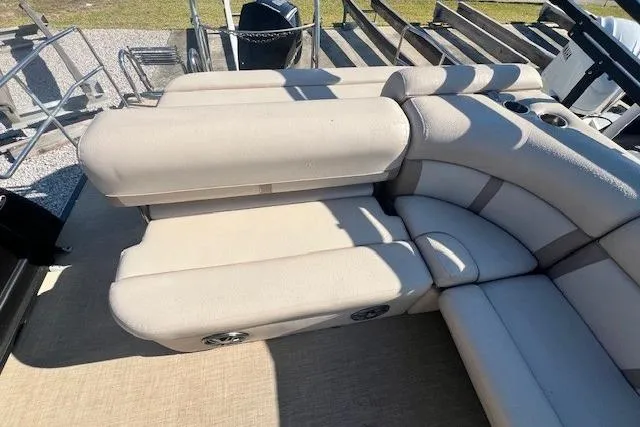 Slide: The Image of 2019 Harris Cruiser 250 boat seat storage compartment with beige upholstery and cup holders. - 8