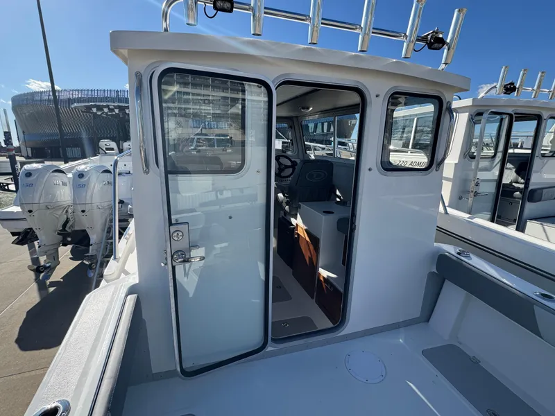 Slide: The Image of 2025 Defiance San Juan 220 boat with open cabin door, docked with multiple engines. - 23