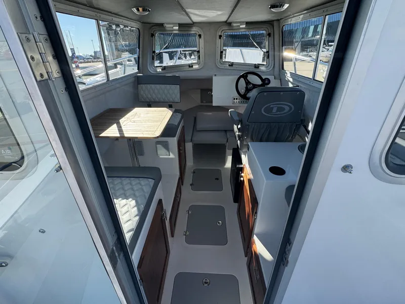 Slide: The Image of Interior of 2025 Defiance San Juan 220 boat, featuring seating, steering wheel, and windows. - 24