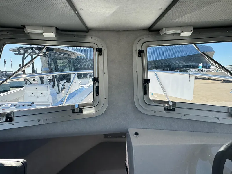Slide: The Image of Interior view of 2025 Defiance San Juan 220 boat, showcasing windows and exterior marina. - 32