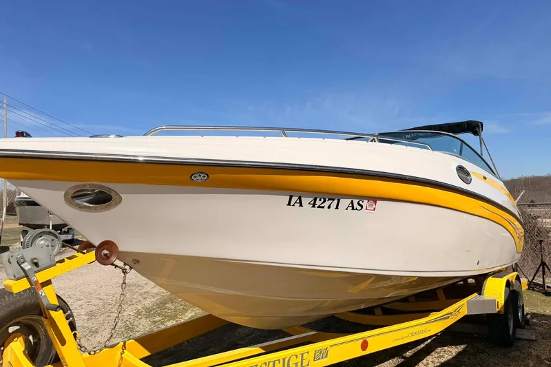 The Image of 2005 Crownline 270 BR boat on trailer, featuring a sleek yellow and white design. - 1