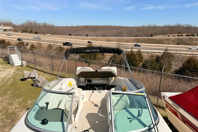 Slide: The Image of 2005 Crownline 270 BR boat parked near highway, showcasing open deck and windshield. - 15