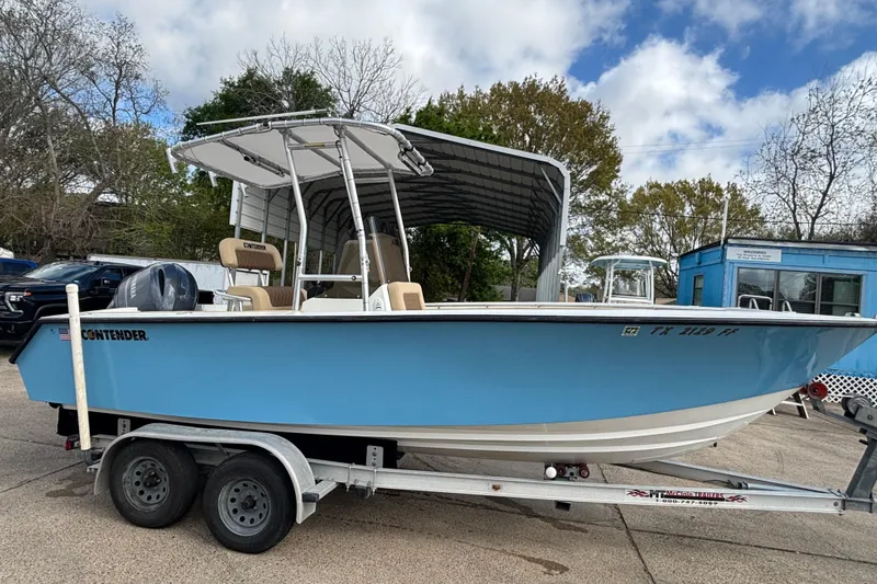 The Image of 1999 Contender 21 Open boat on trailer, blue hull, parked outdoors. - 1