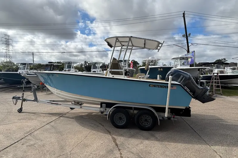 Slide: The Image of 1999 Contender 21 Open boat on trailer, blue hull, parked outdoors under cloudy sky. - 5