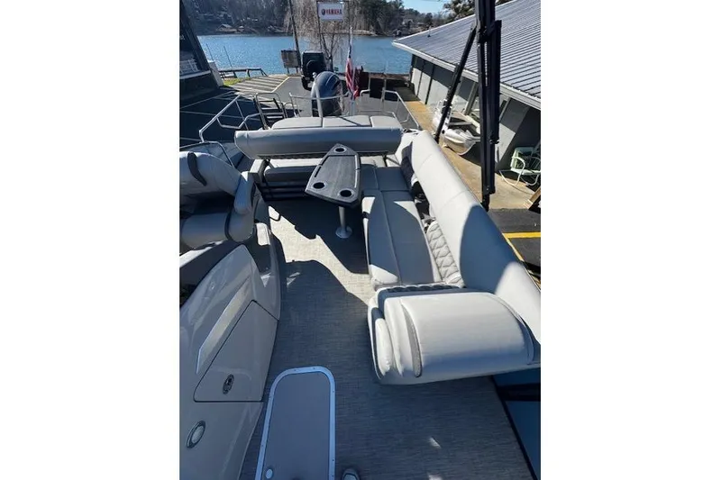 Slide: The Image of 2021 Bennington 23 LXS Swingback pontoon boat with spacious seating and table, docked by a lake. - 3
