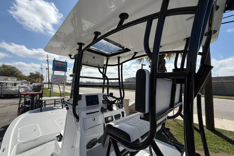 Slide: The Image of 2026 Shallow Sport 25 X3 boat interior with helm and seating under a clear sky. - 23